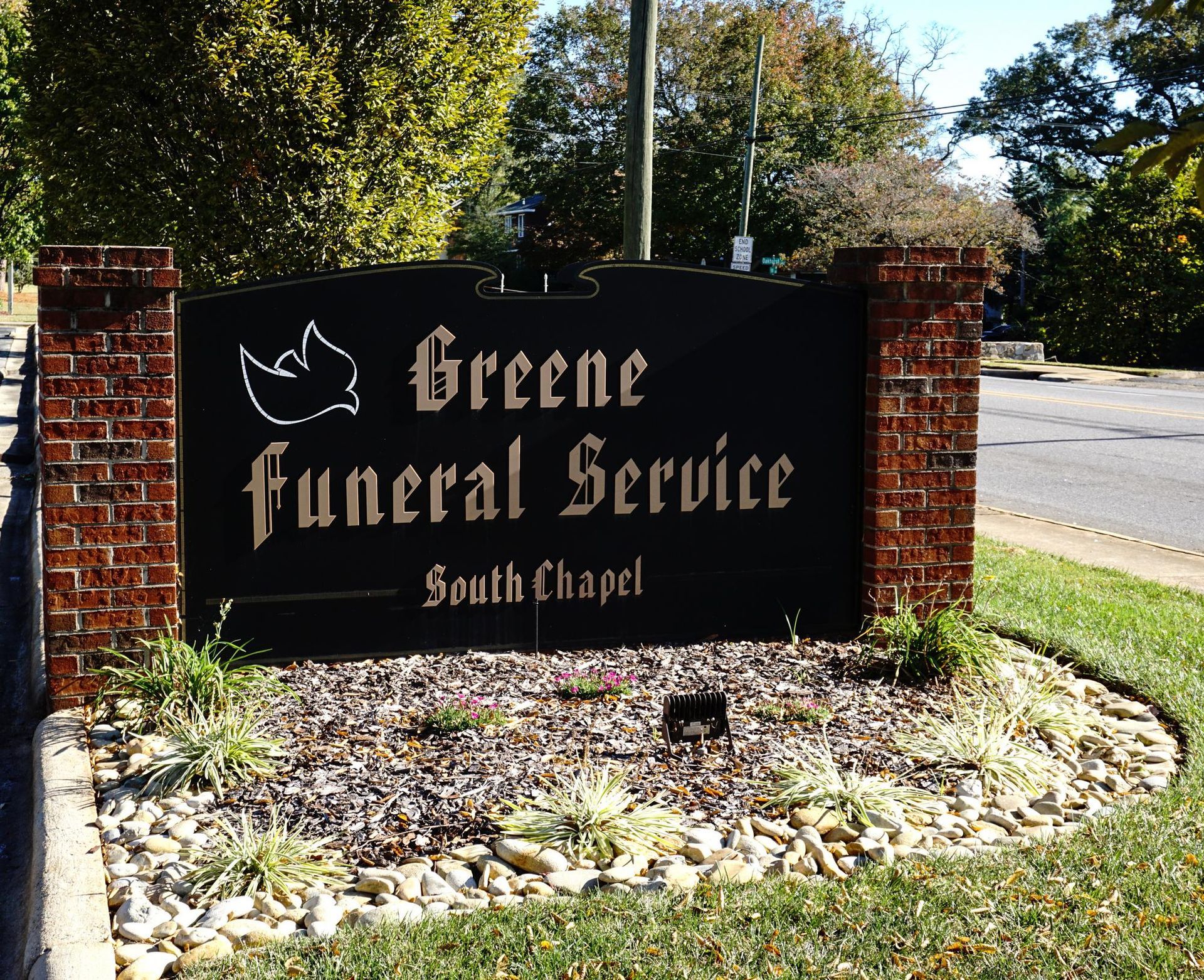 Sign for Greene Funeral Service South Chapel with black lettering and brick accents.