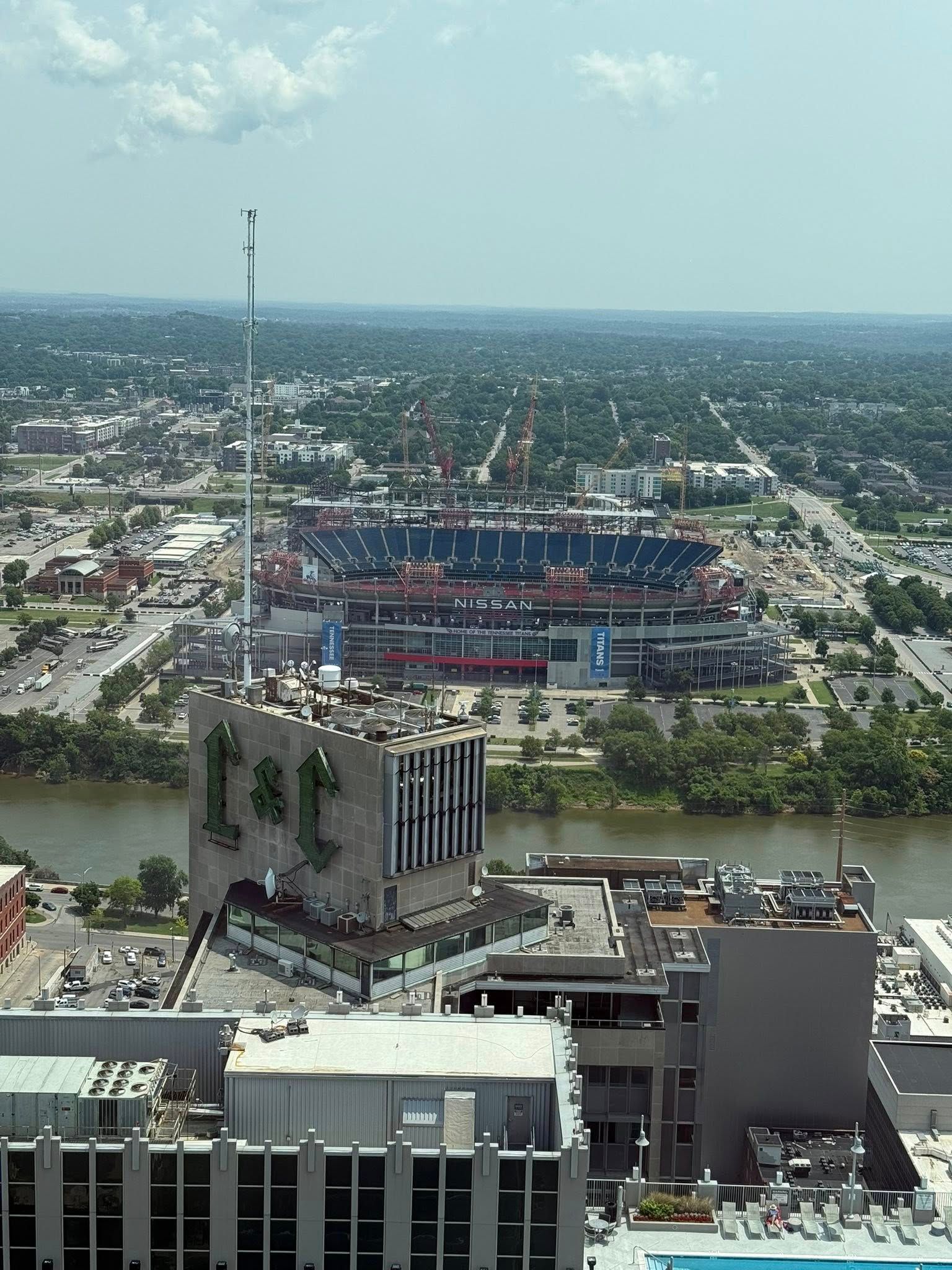 City skyline with a stadium under construction, seen from a high rooftop on a clear day.