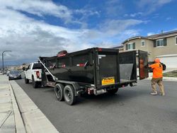 A man is standing next to a dumpster on a trailer.