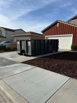 A large dumpster is parked in front of a house.