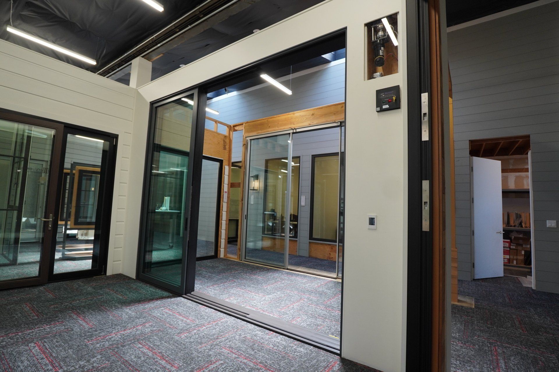 A sliding door in a showroom that has a motorized  automation unit on display inside the wall located to the right side of the door.