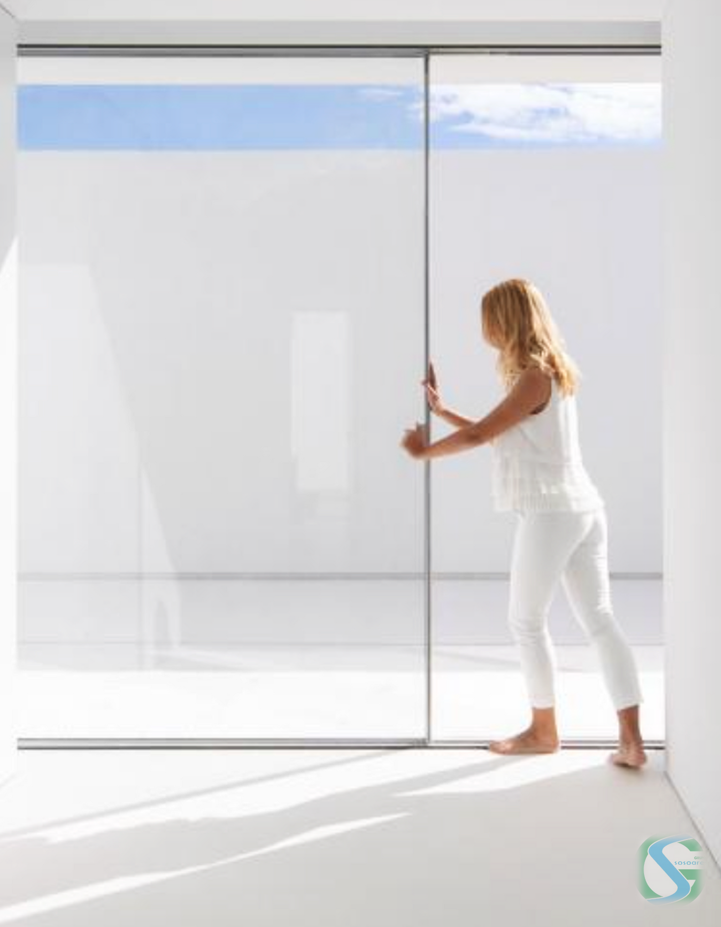Lady dressed in all white opening a sliding glass door with all white background.