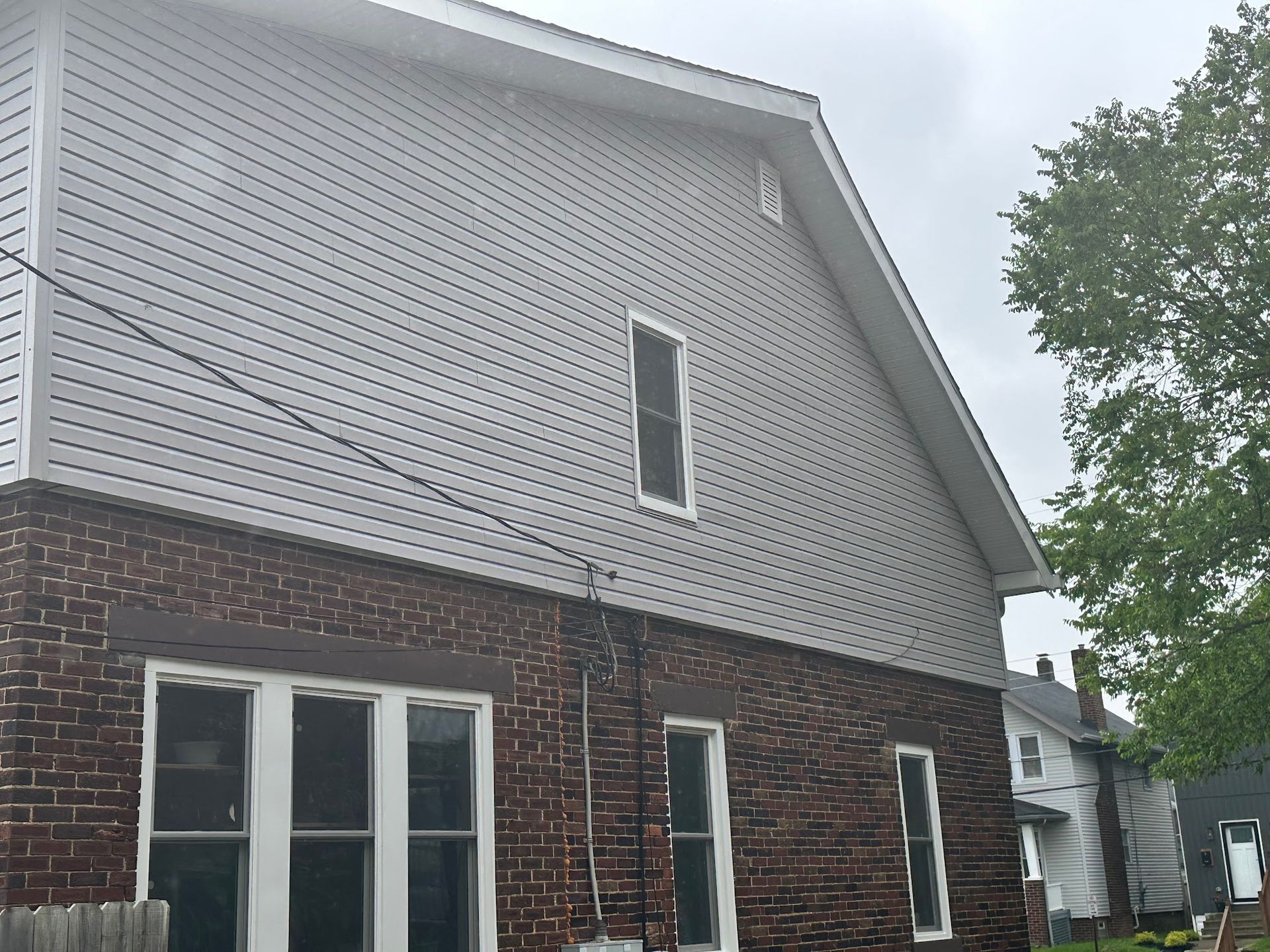 Brick building with gray siding. Cloudy sky.