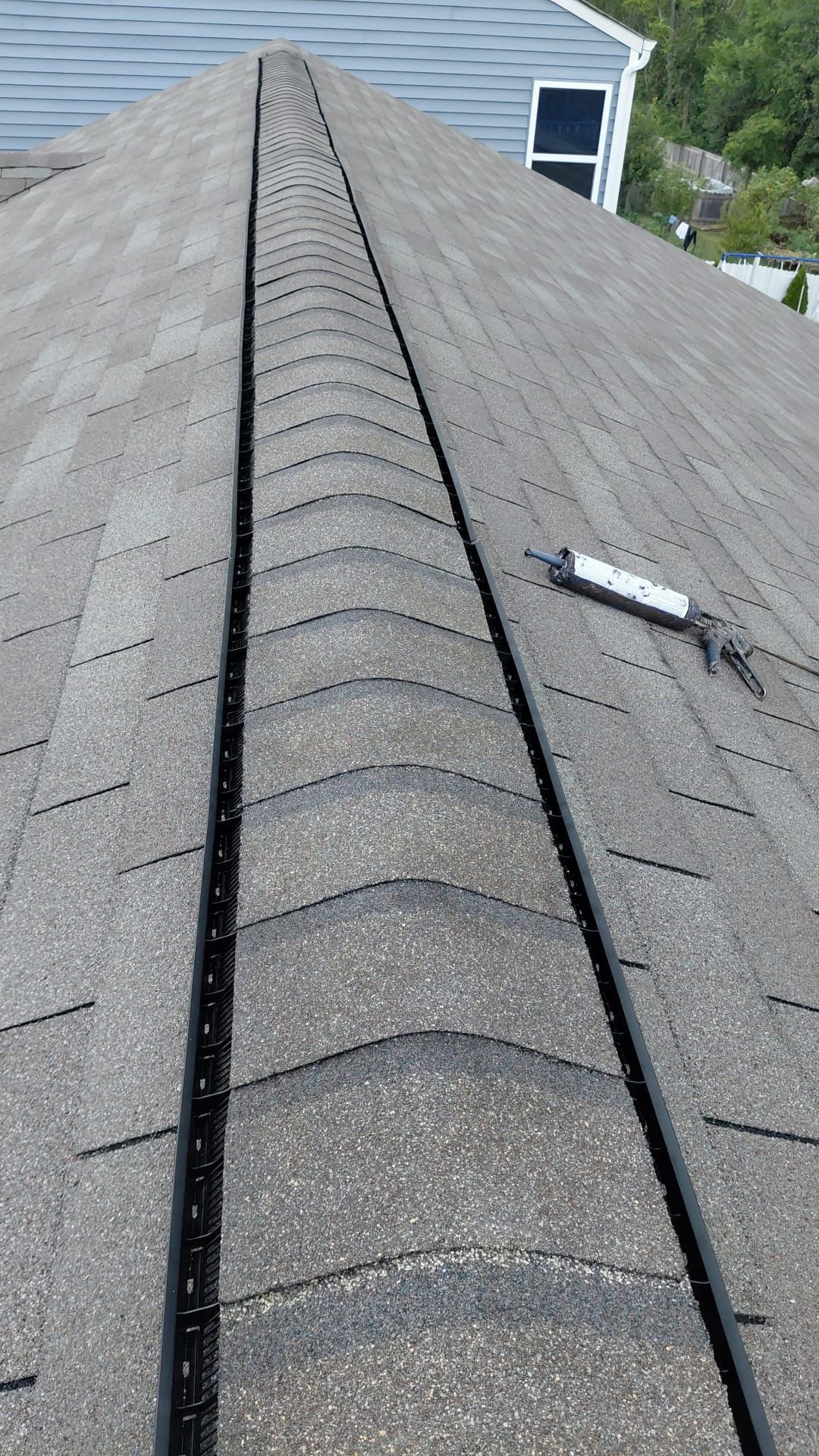 View from rooftop of installed roof vent with asphalt shingles.