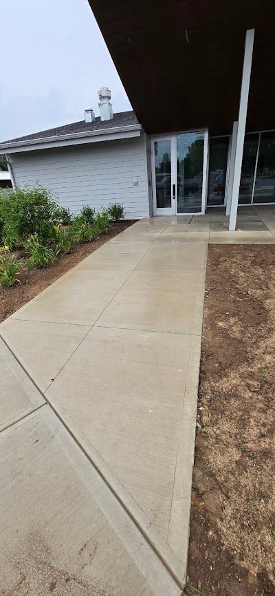 A concrete walkway leading to a building entrance with glass doors.