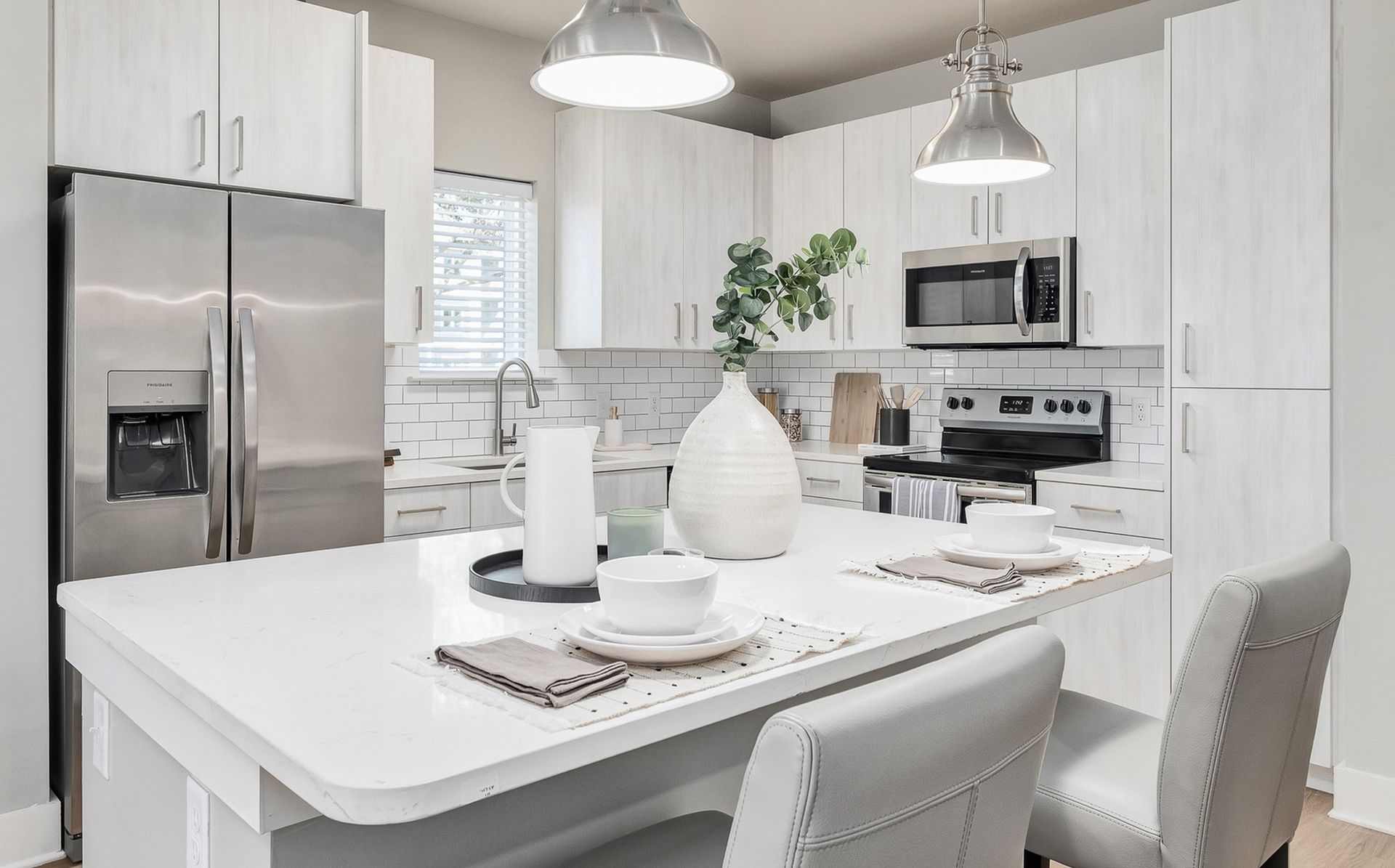 A kitchen with white cabinets , stainless steel appliances , and a large island.
