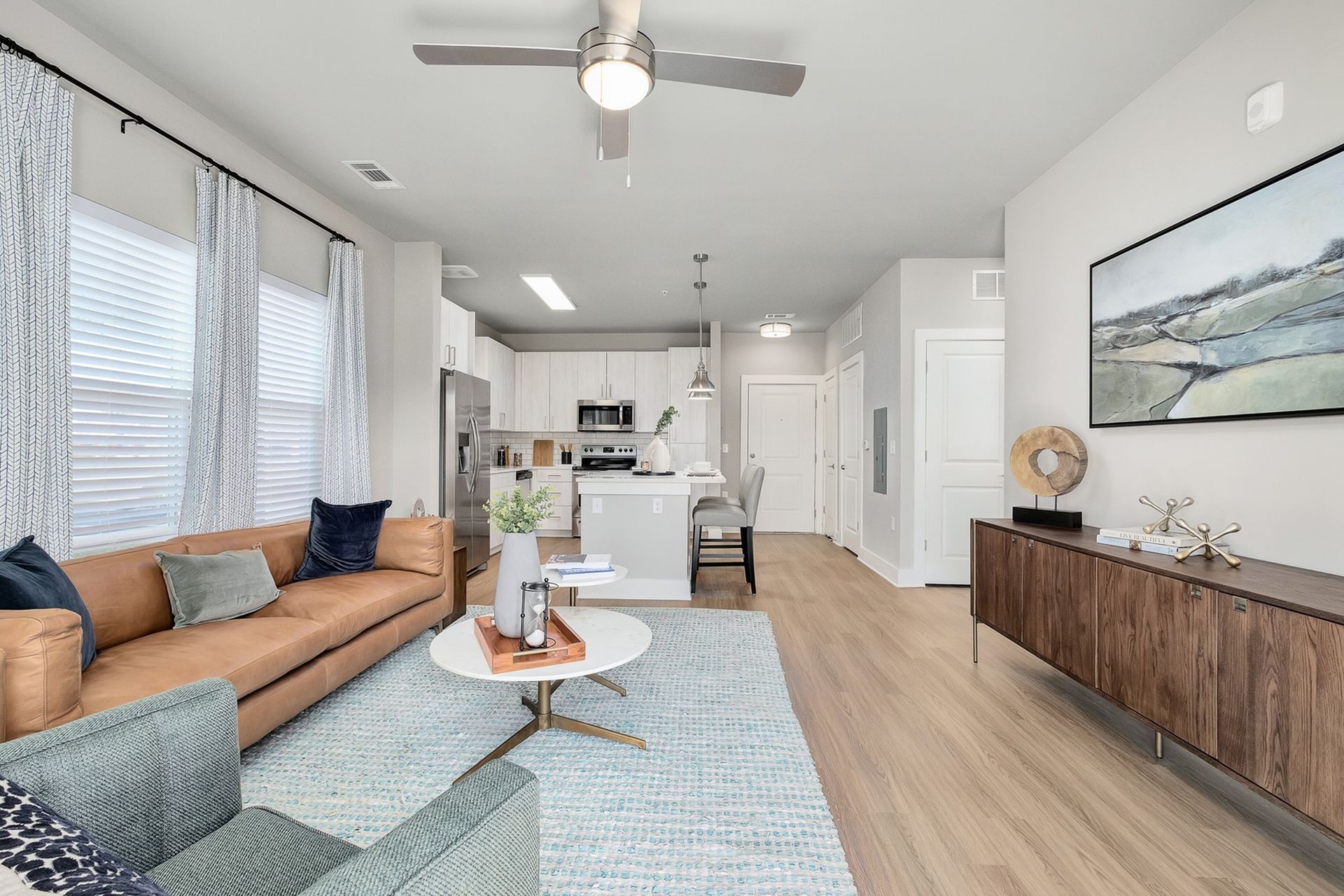 A living room with a couch , chair , table and ceiling fan.