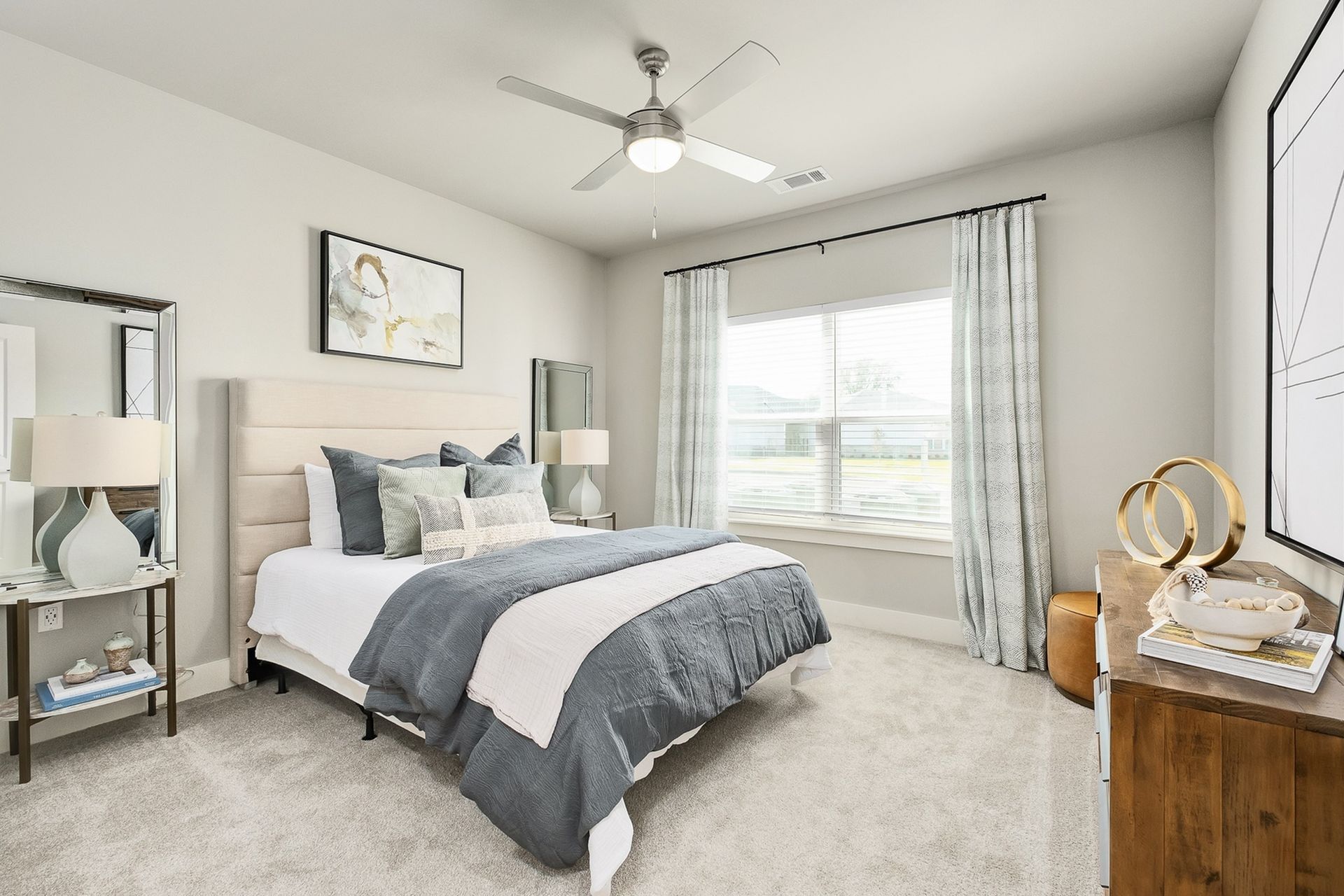A bedroom with a bed , dresser , nightstand , mirror and ceiling fan.