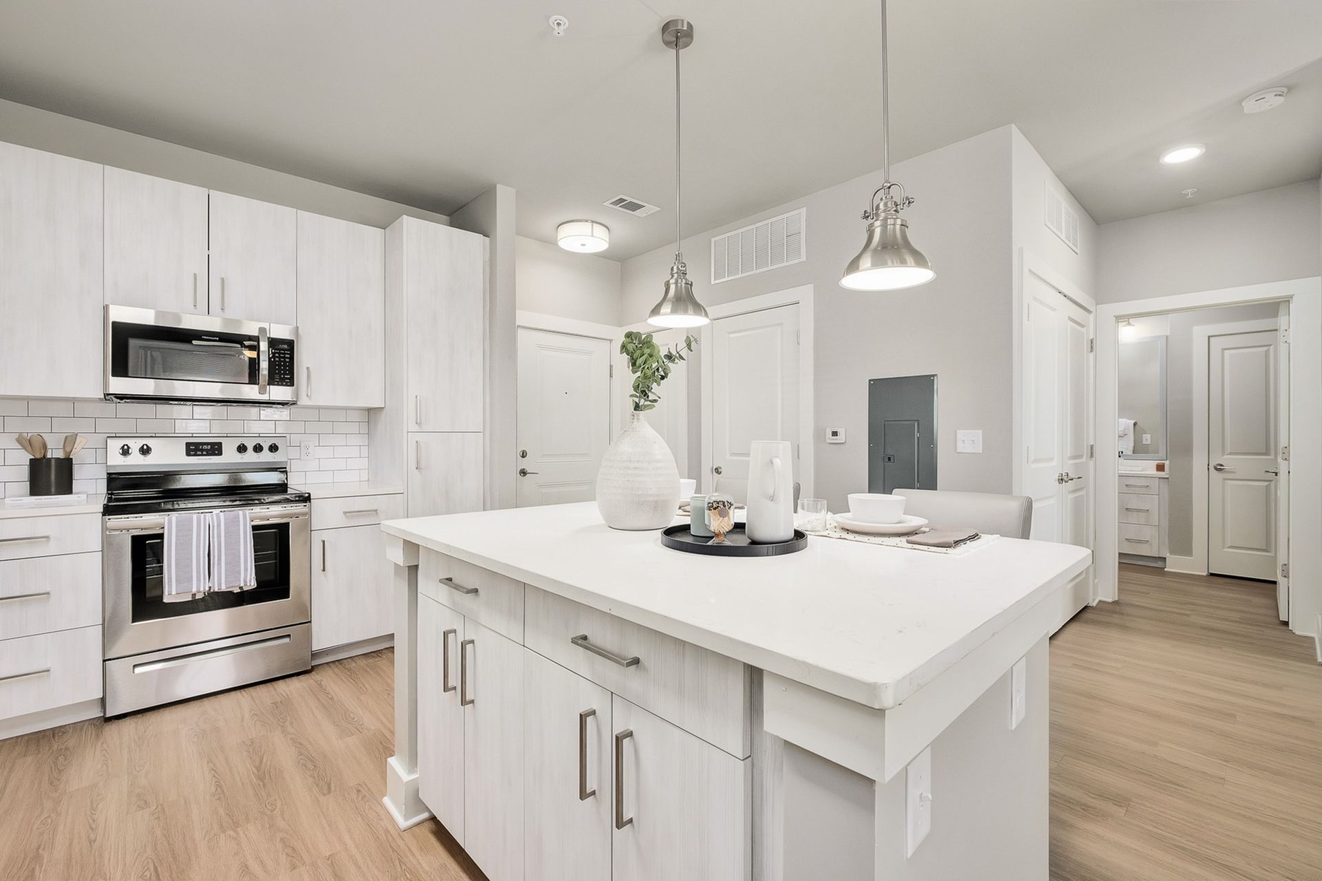 A kitchen with white cabinets , stainless steel appliances , and a large island.