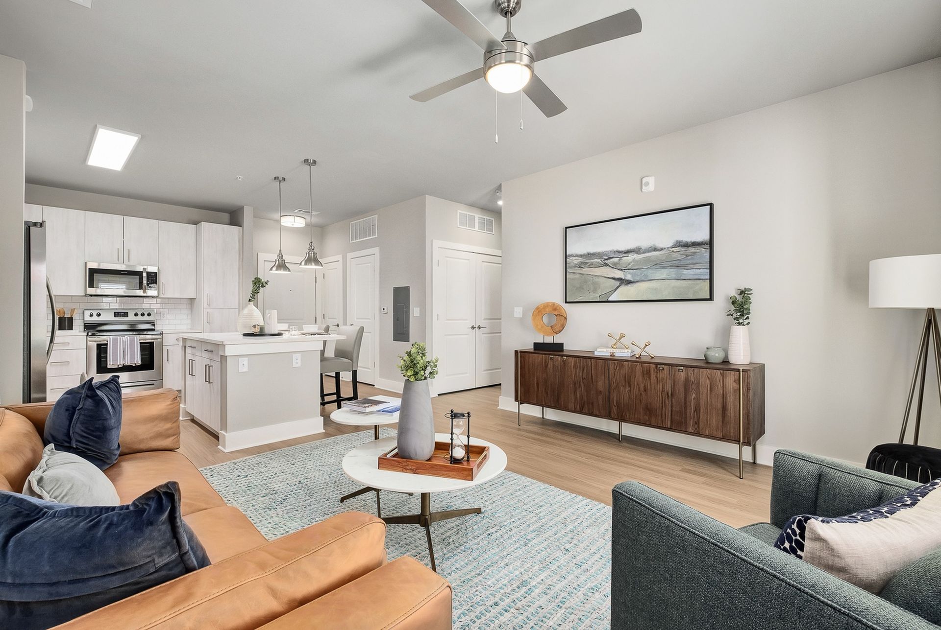 A living room with a couch , chair , coffee table and ceiling fan.