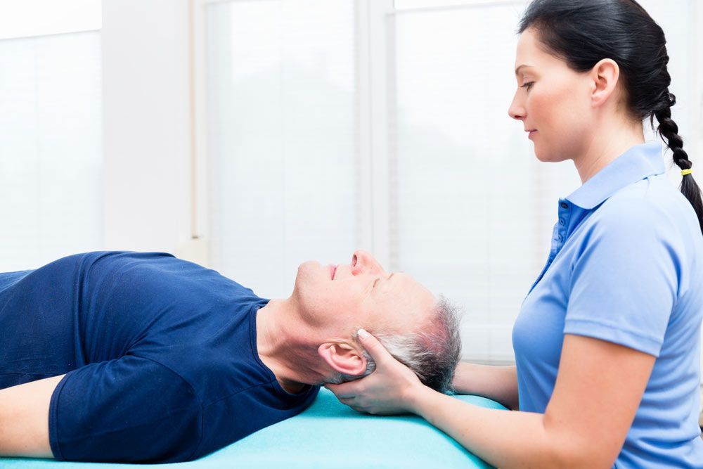 A Man Is Laying On A Table Getting A Head Massage From A Woman — Phoenix Mandorla In Rockhampton City, QLD