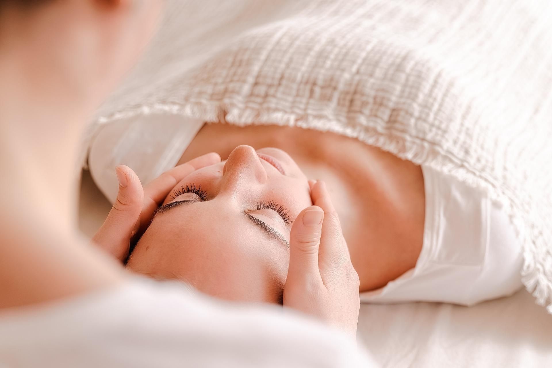 A woman is laying on a bed getting a facial massage — Phoenix Mandorla In Rockhampton City, QLD
