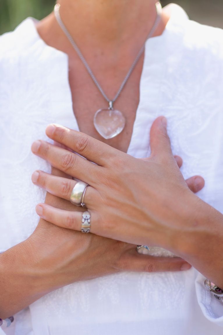 Woman Wearing a Necklace and a Ring is Holding Her Hands to Her Chest — Phoenix Mandorla In Rockhampton City, QLD