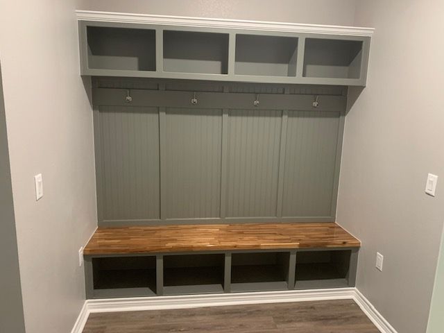 A mud room with a wooden bench and shelves.
