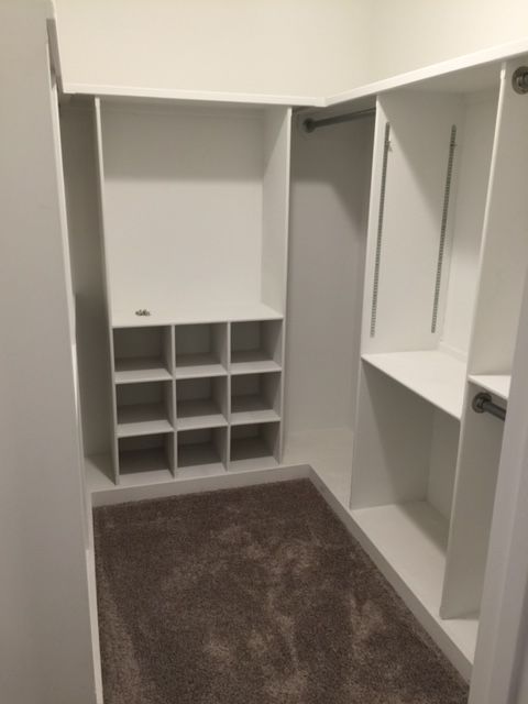 A walk in closet with white shelves and brown carpet