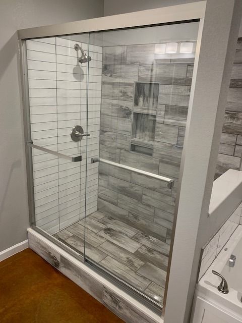 A bathroom with a sliding glass shower door and a tub.