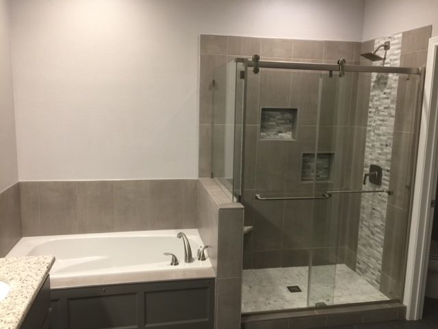 A bathroom with a tub and a shower with a sliding glass door.