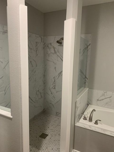 A bathroom with a tub , shower , and mirror.