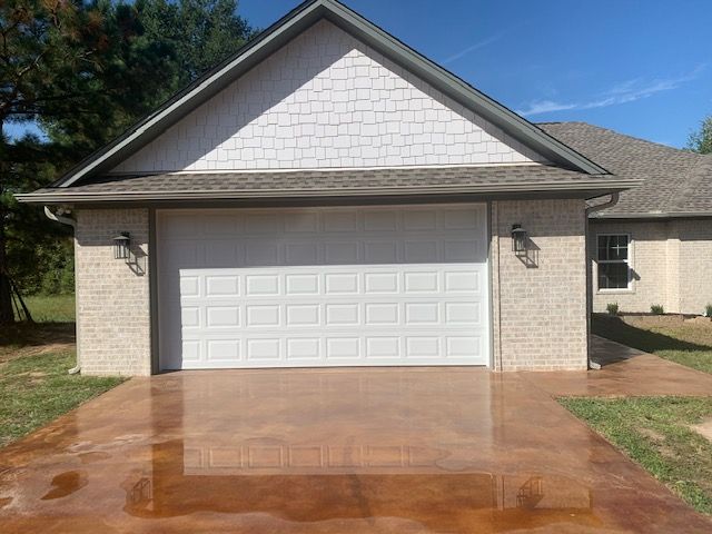 A white garage door is sitting in front of a brick house.