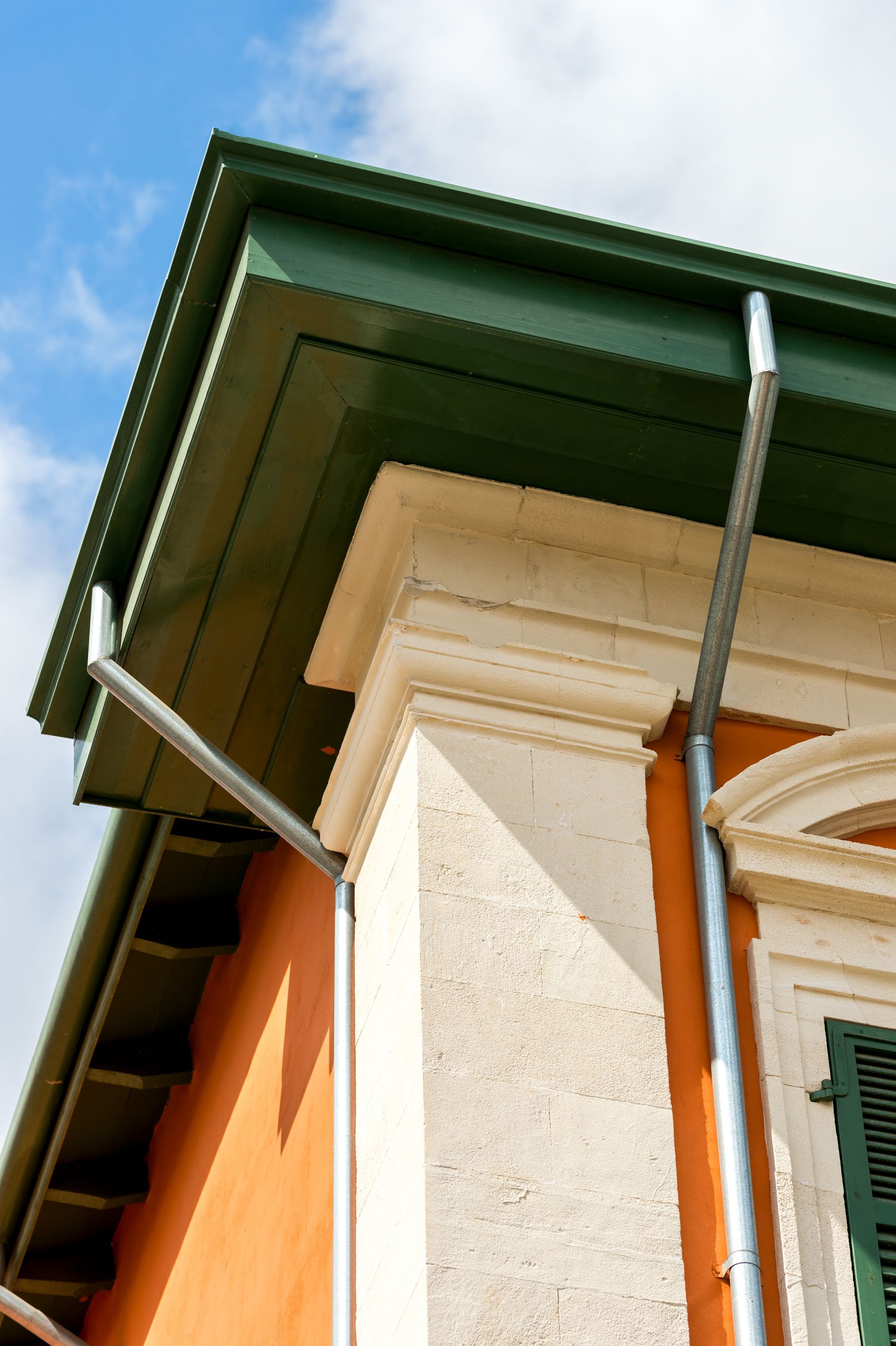 A green gutter on the side of a building