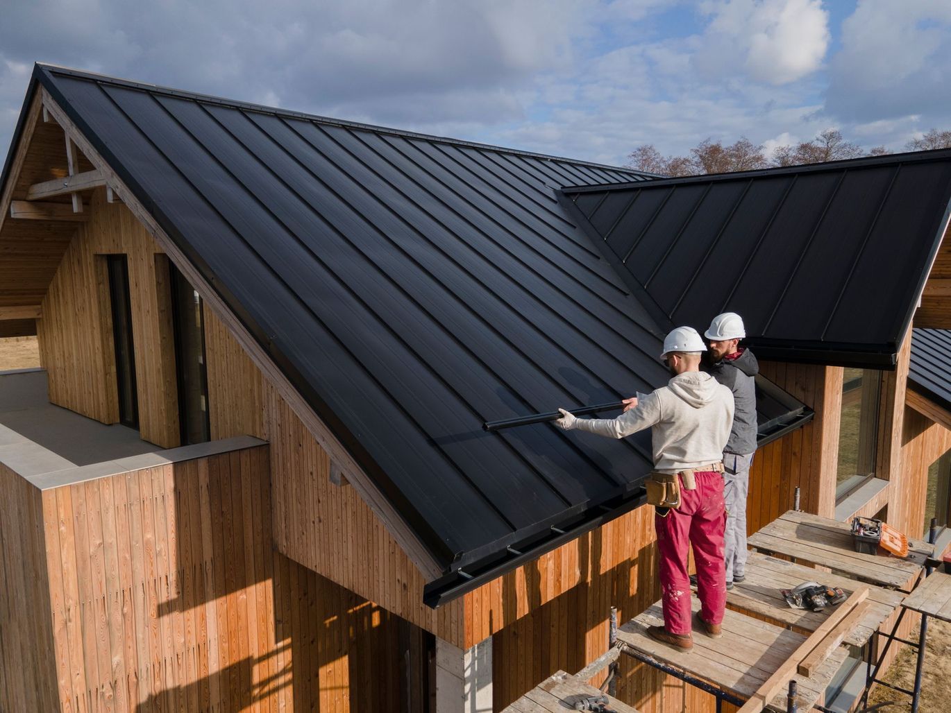 Two men are working on the roof of a wooden house.