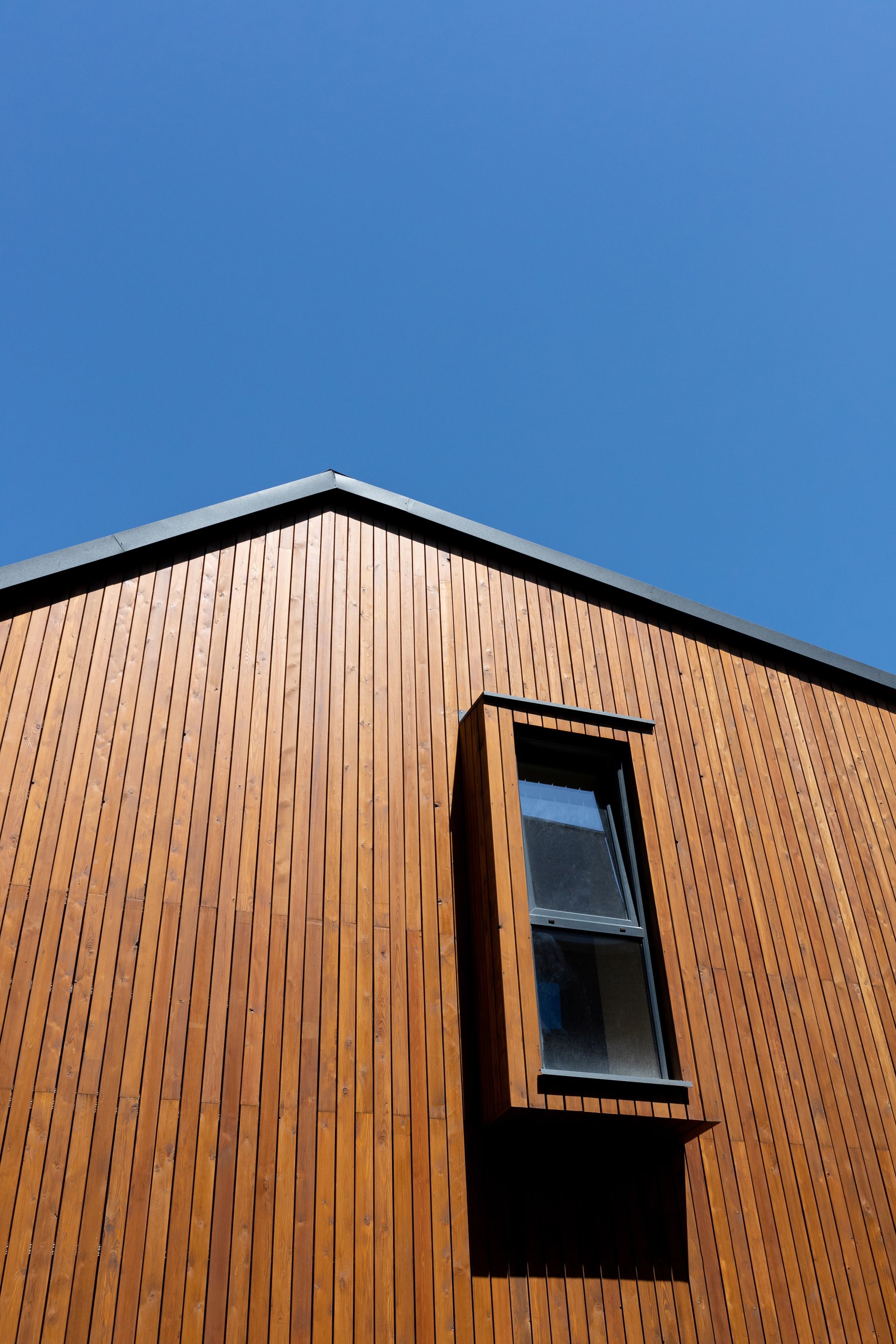 A wooden building with a window and a blue sky in the background