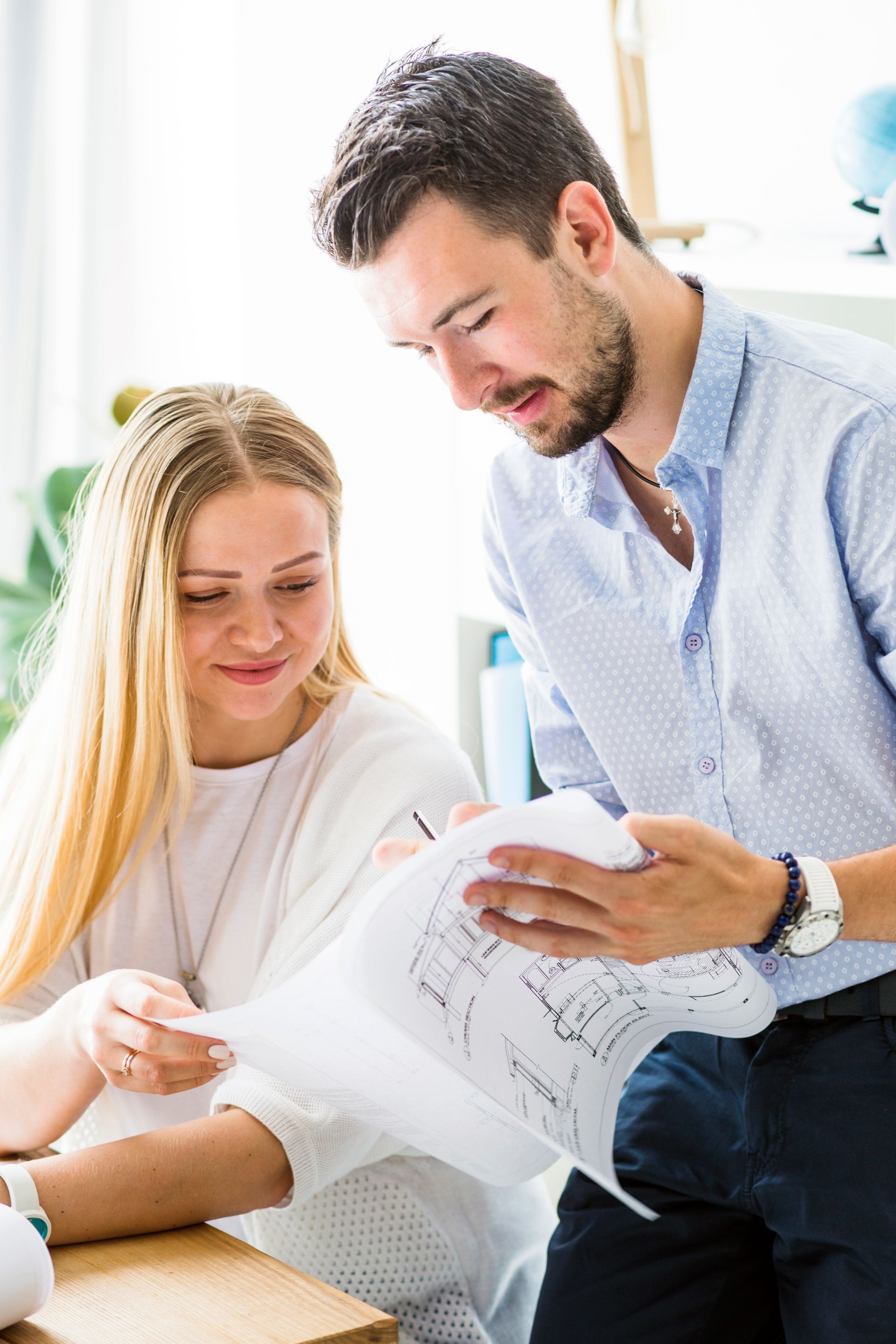 A man and a woman are looking at a blueprint together.