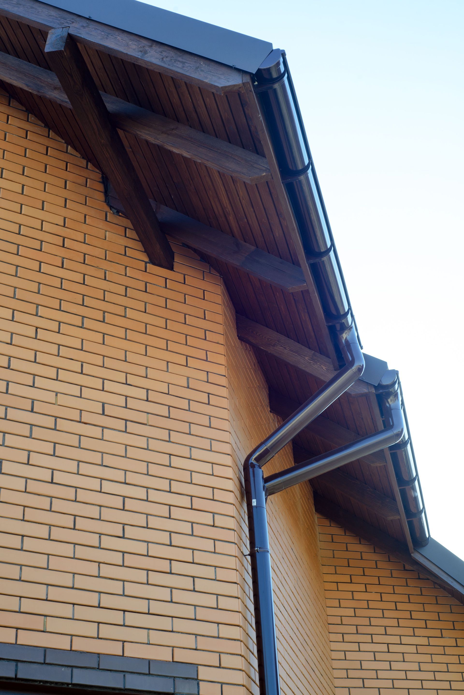 A brick building with a wooden roof and gutters