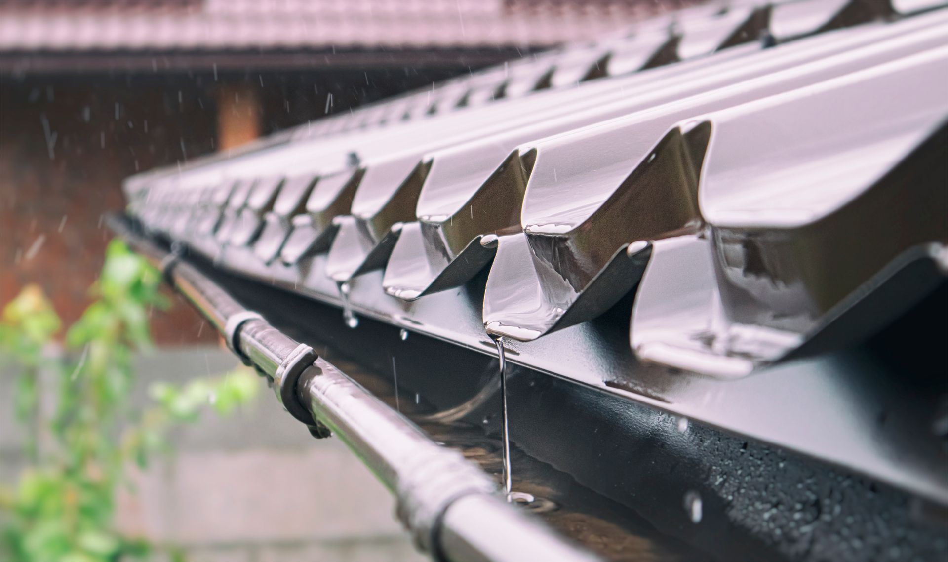 A close up of a gutter on a roof in the rain.