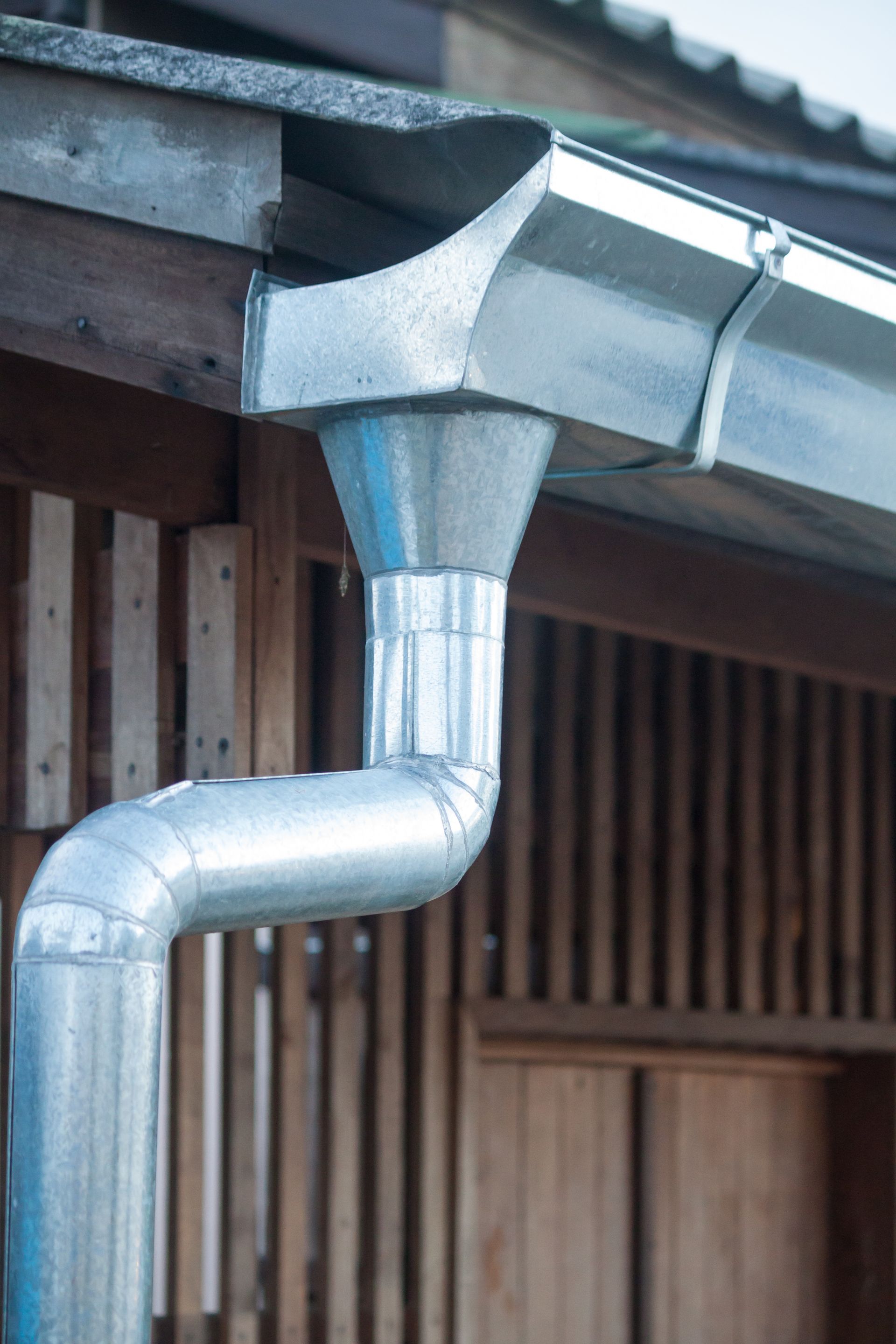 A close up of a metal rain gutter on the side of a building.