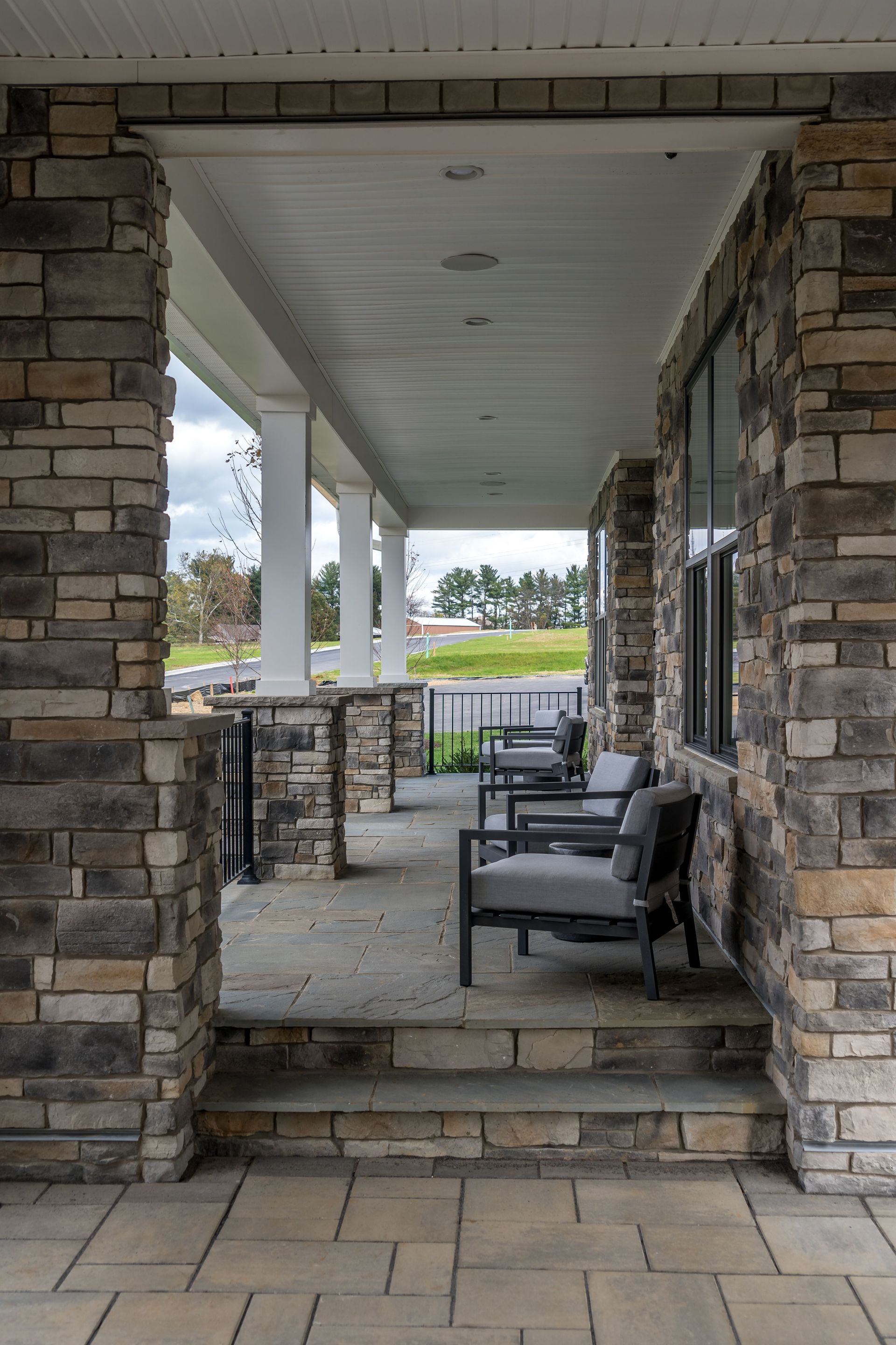 A stone porch with chairs and steps leading to it.