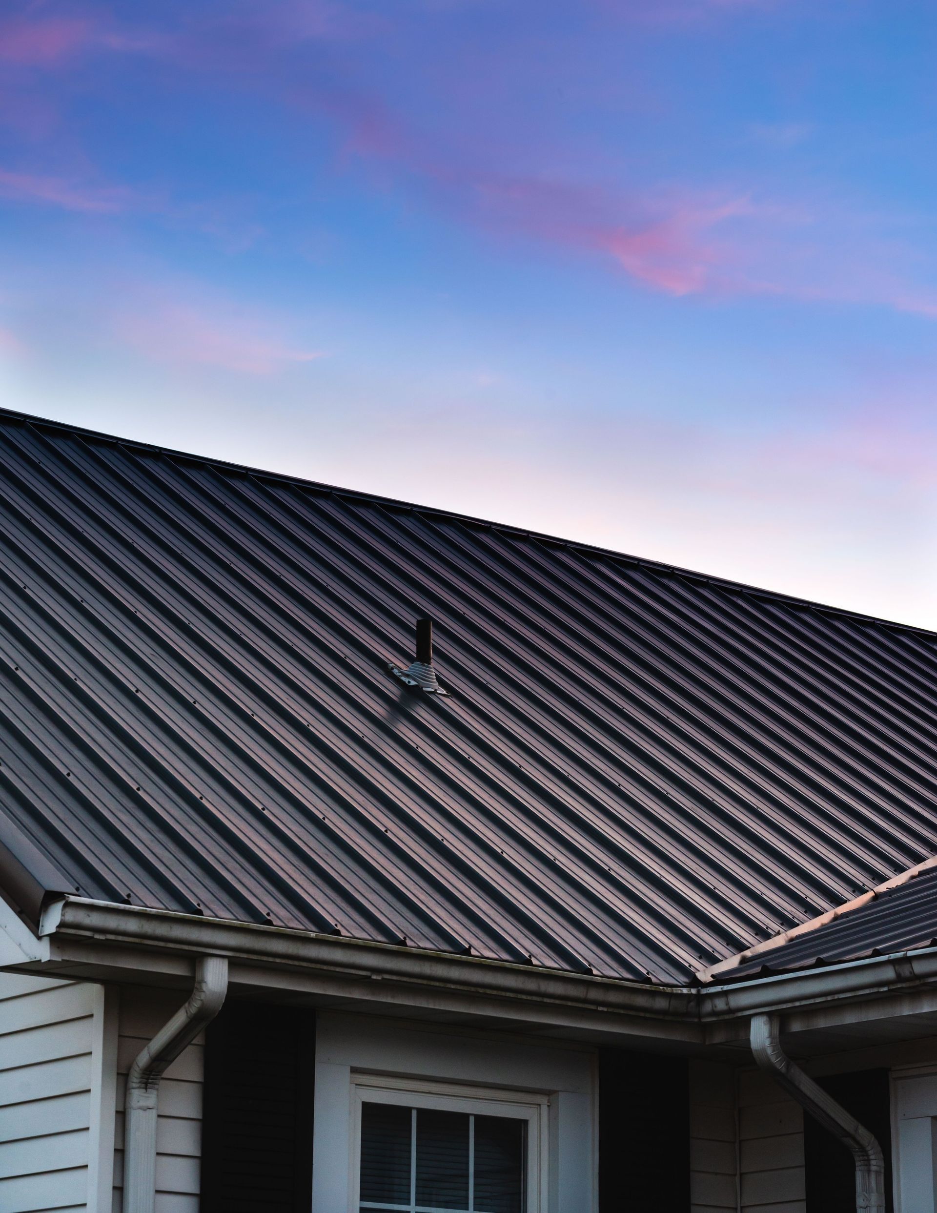 A house with a metal roof and a blue sky in the background.