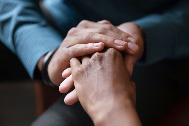 up close focus on hands that are being held by each other coping with grief and loss