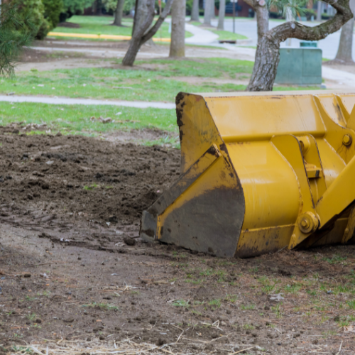 A yellow bulldozer is moving dirt in a park.