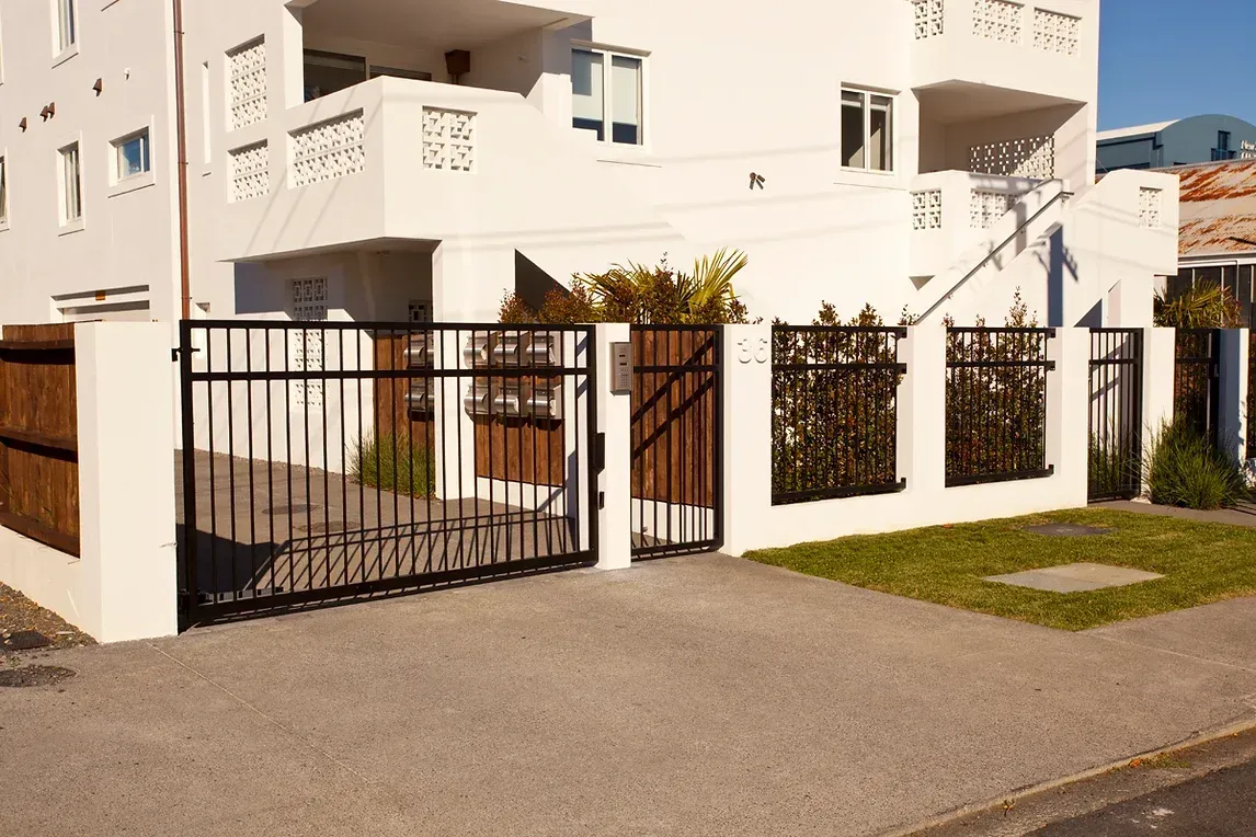 A white building with a black gate in front of it