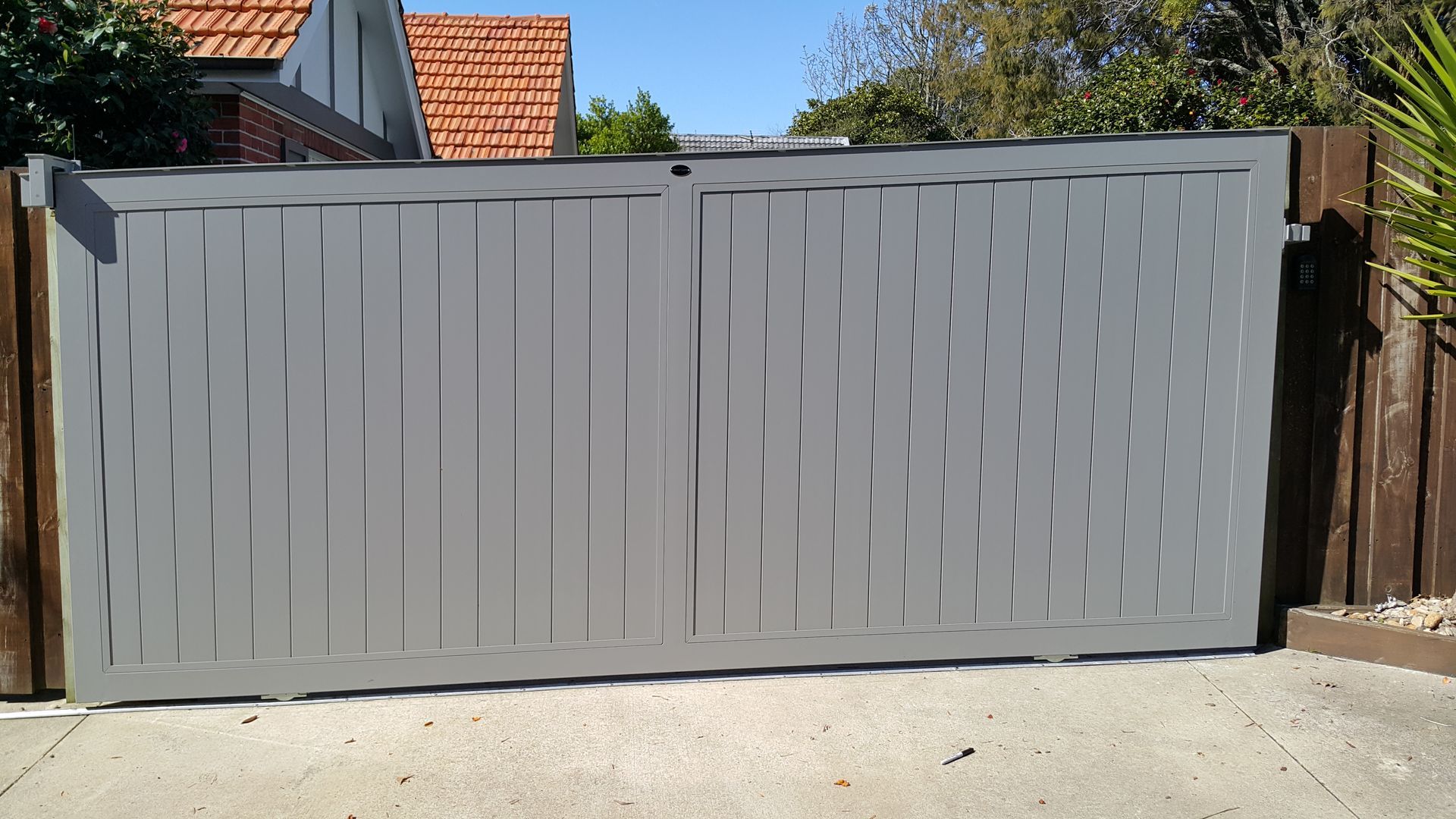 A gray gate with a wooden fence behind it
