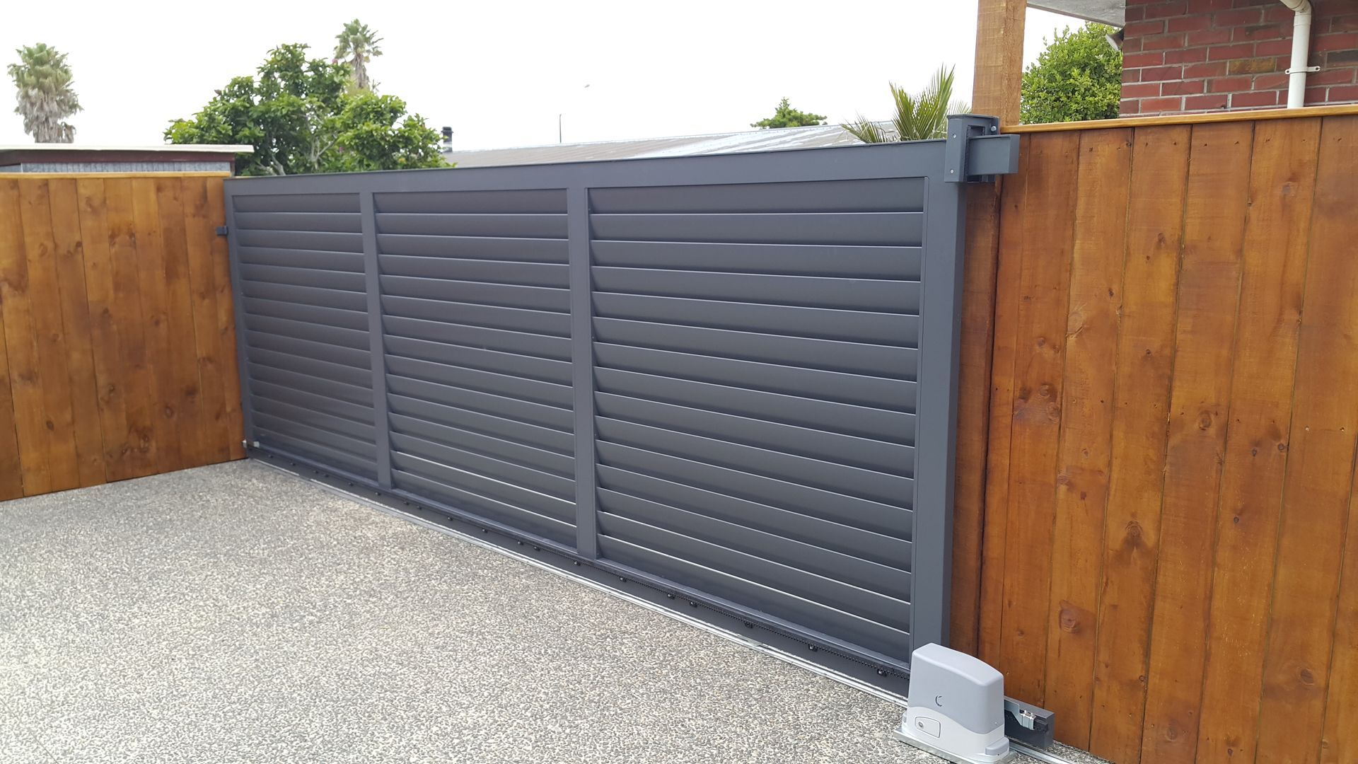 A sliding gate with a wooden fence behind it.