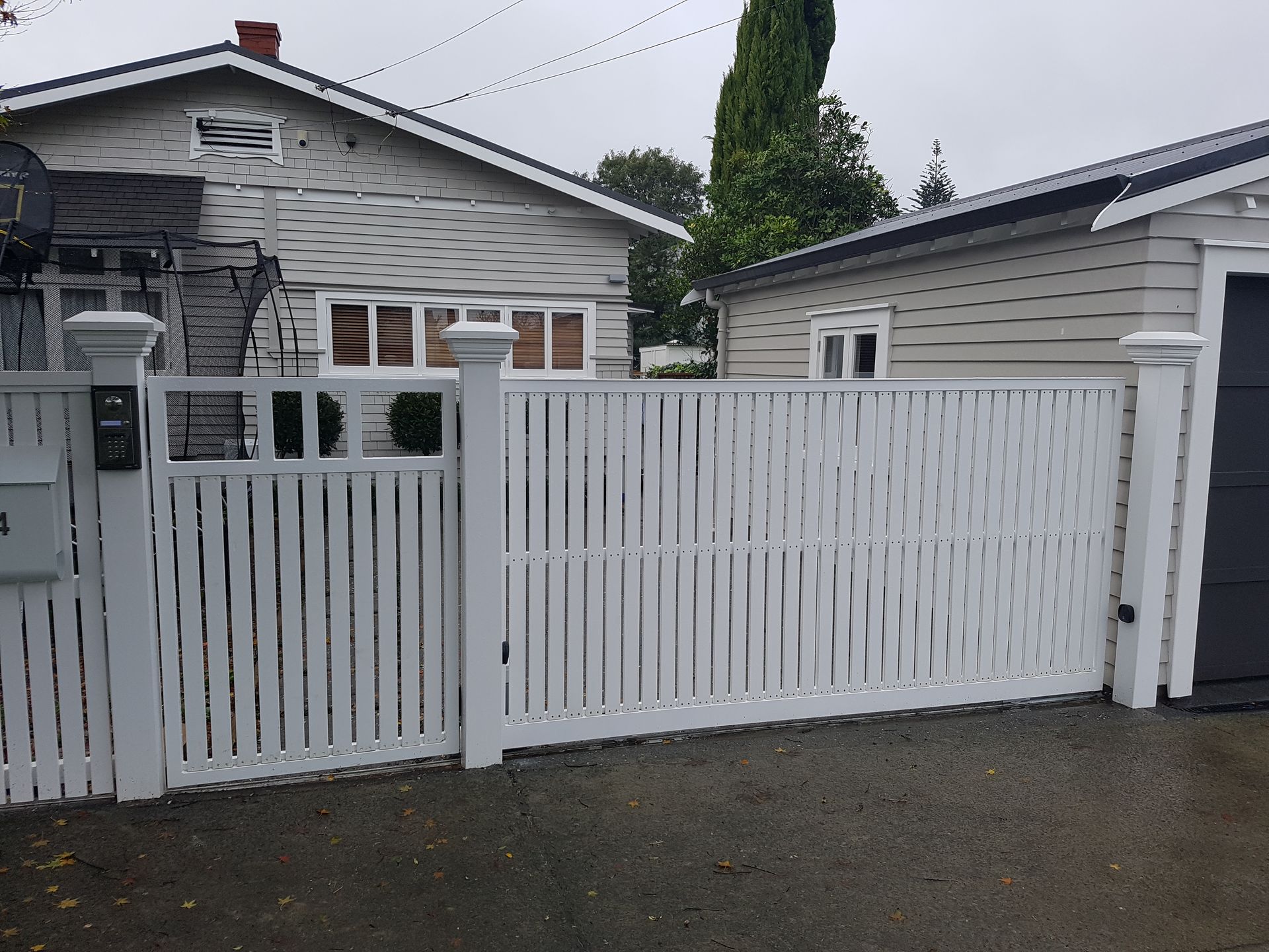 A white fence is surrounding a house and garage.