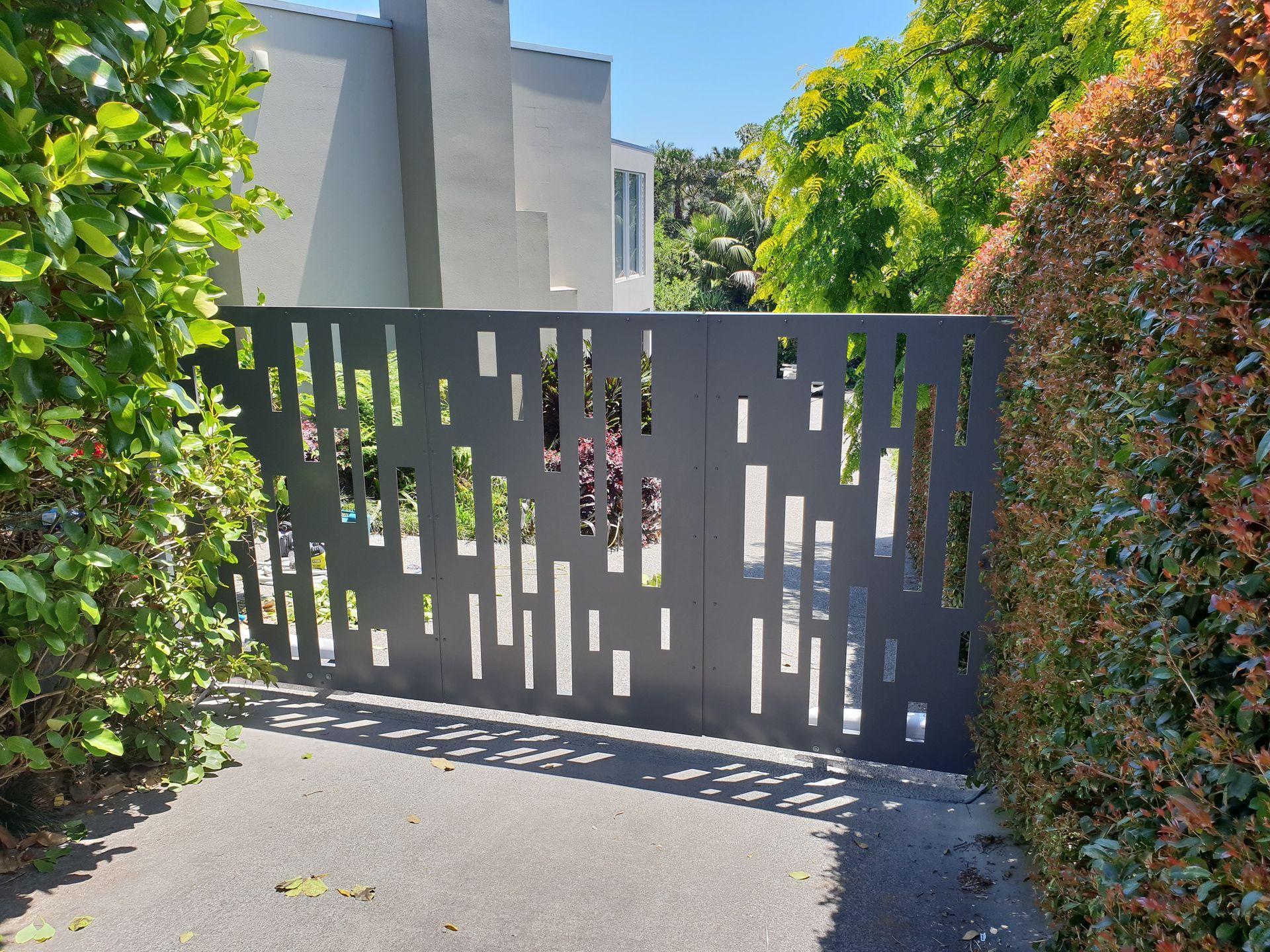 A fence with holes in it is surrounded by trees and bushes