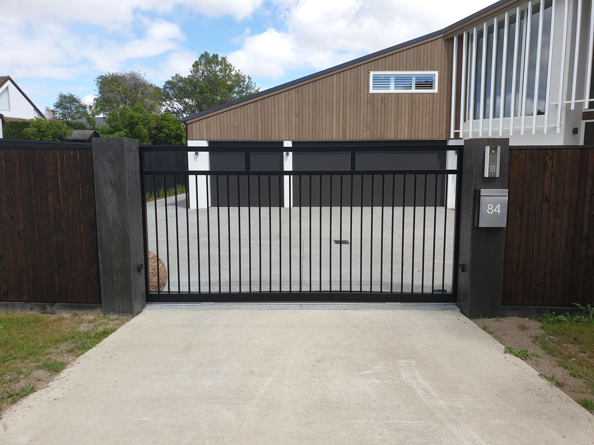 A house with a sliding gate and a mailbox in front of it