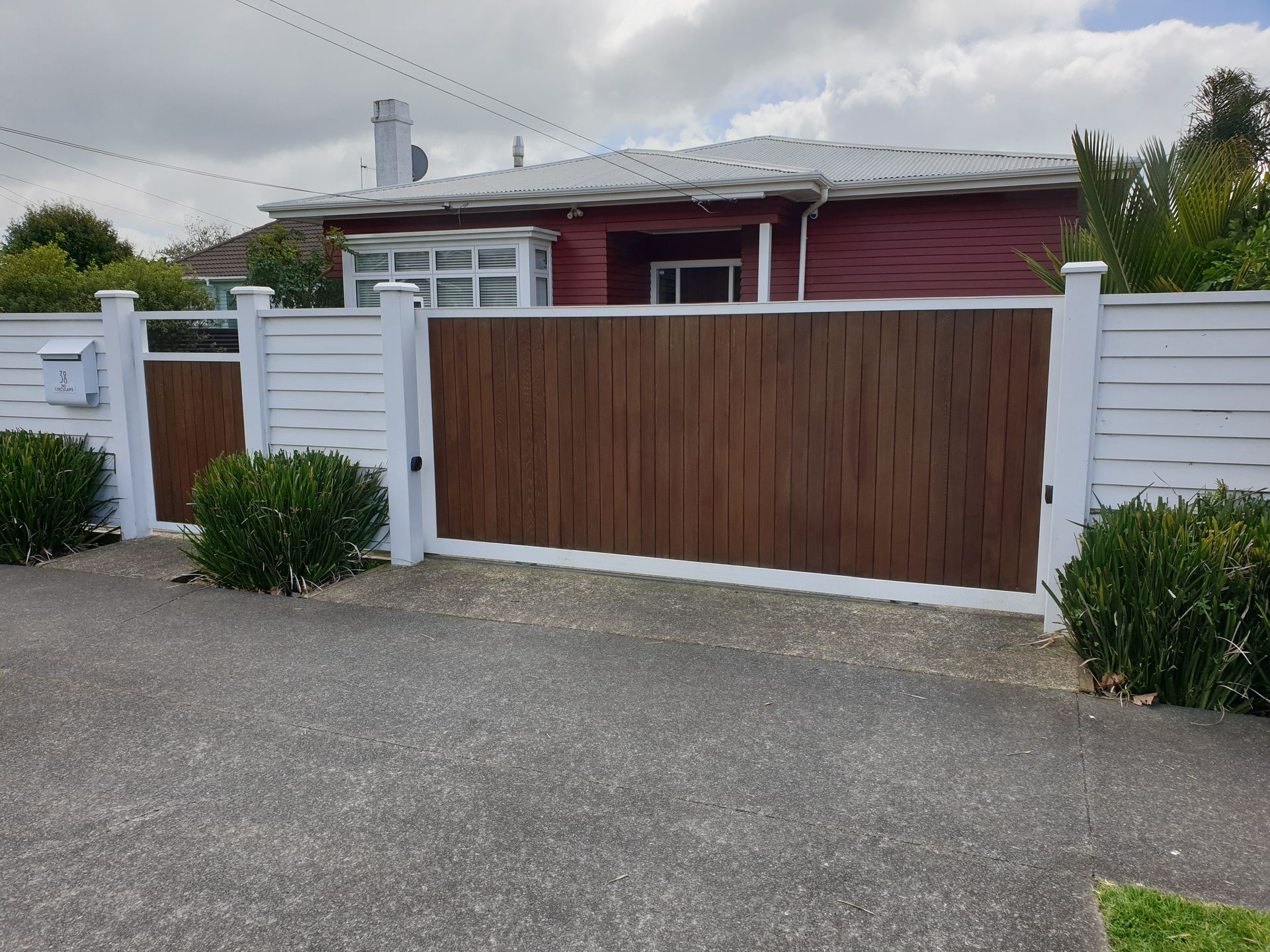 A red house with a white fence and a wooden gate