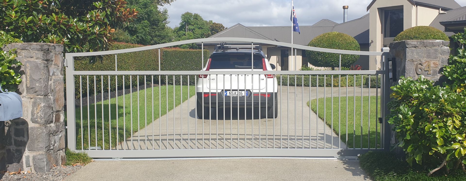 A car is driving through a gate in front of a house
