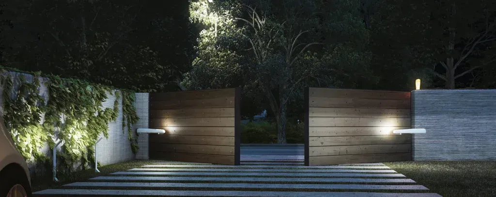A person is standing in front of a wooden gate at night.