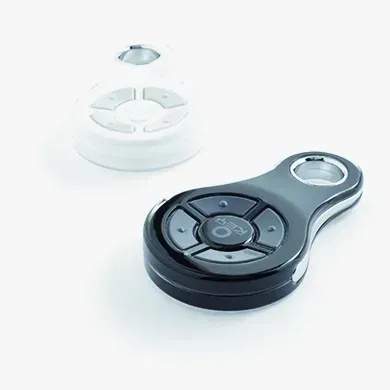 Two remote controls , one black and one white , are on a white surface.