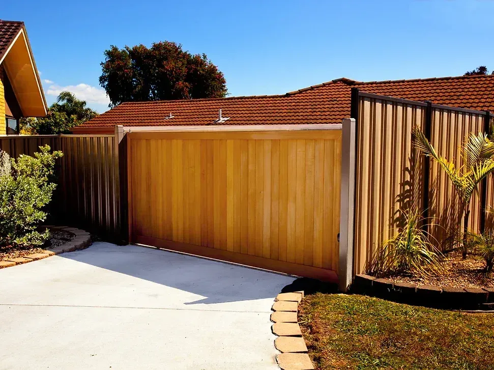 A wooden fence surrounds a driveway in front of a house