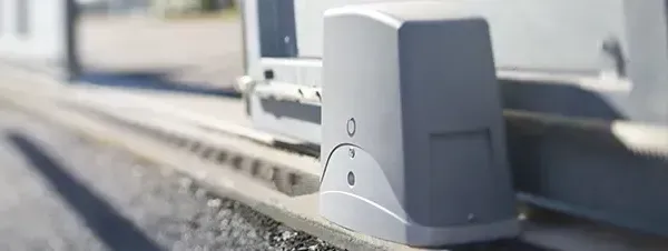 A close up of a sliding gate motor on the side of a road.