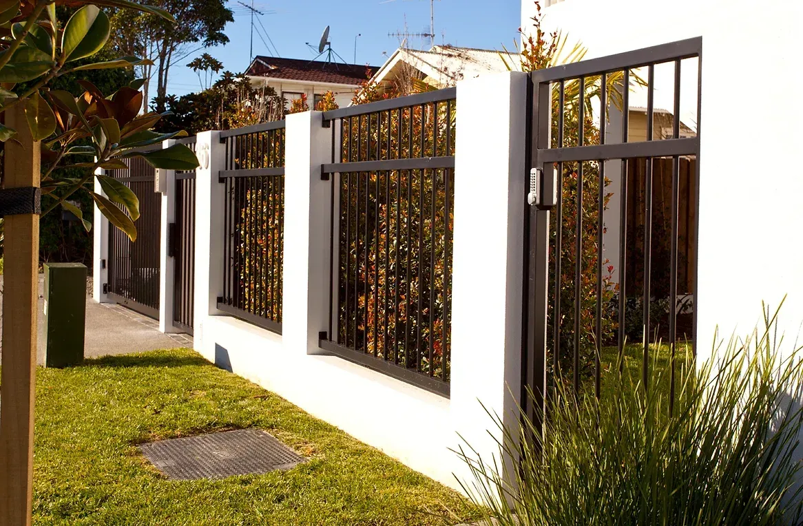 A white wall with a black fence and a gate