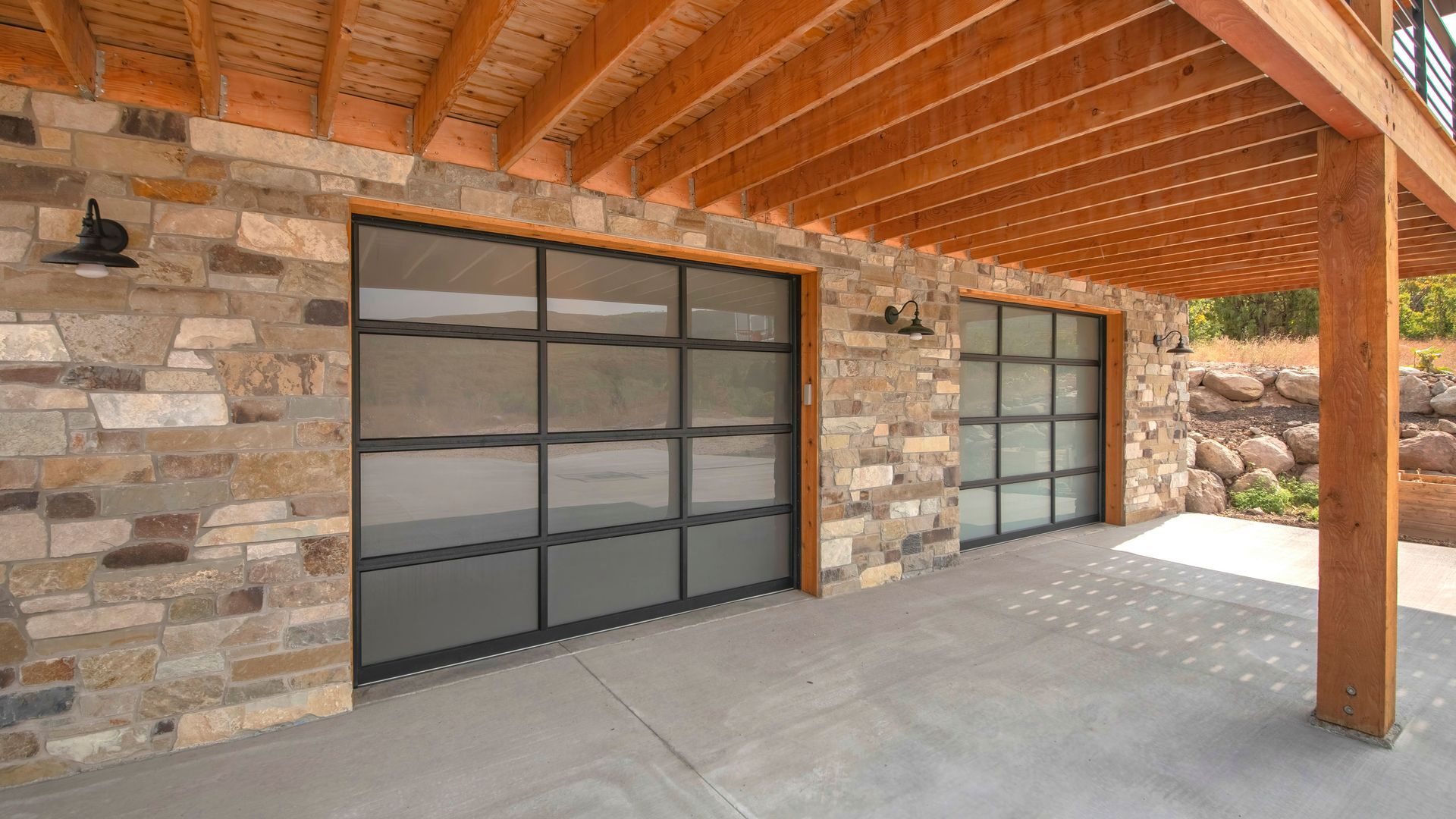 Woman in straw hat smiles, holding wine glass near a lake.