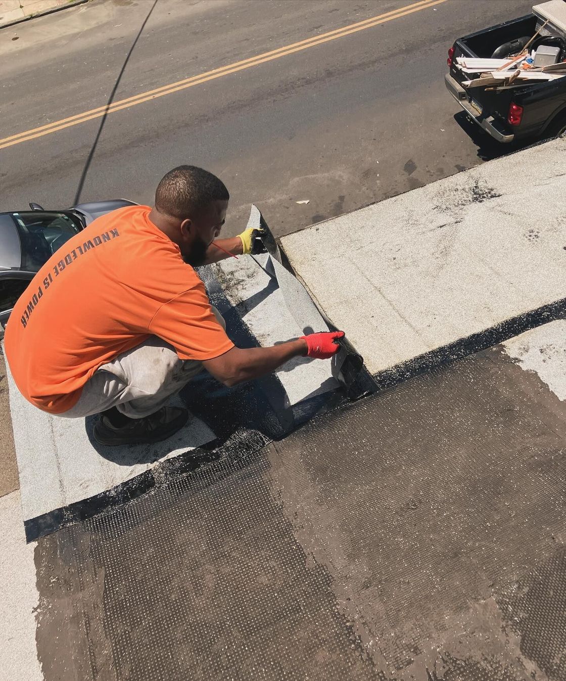 A man in an orange shirt is working on a roof.