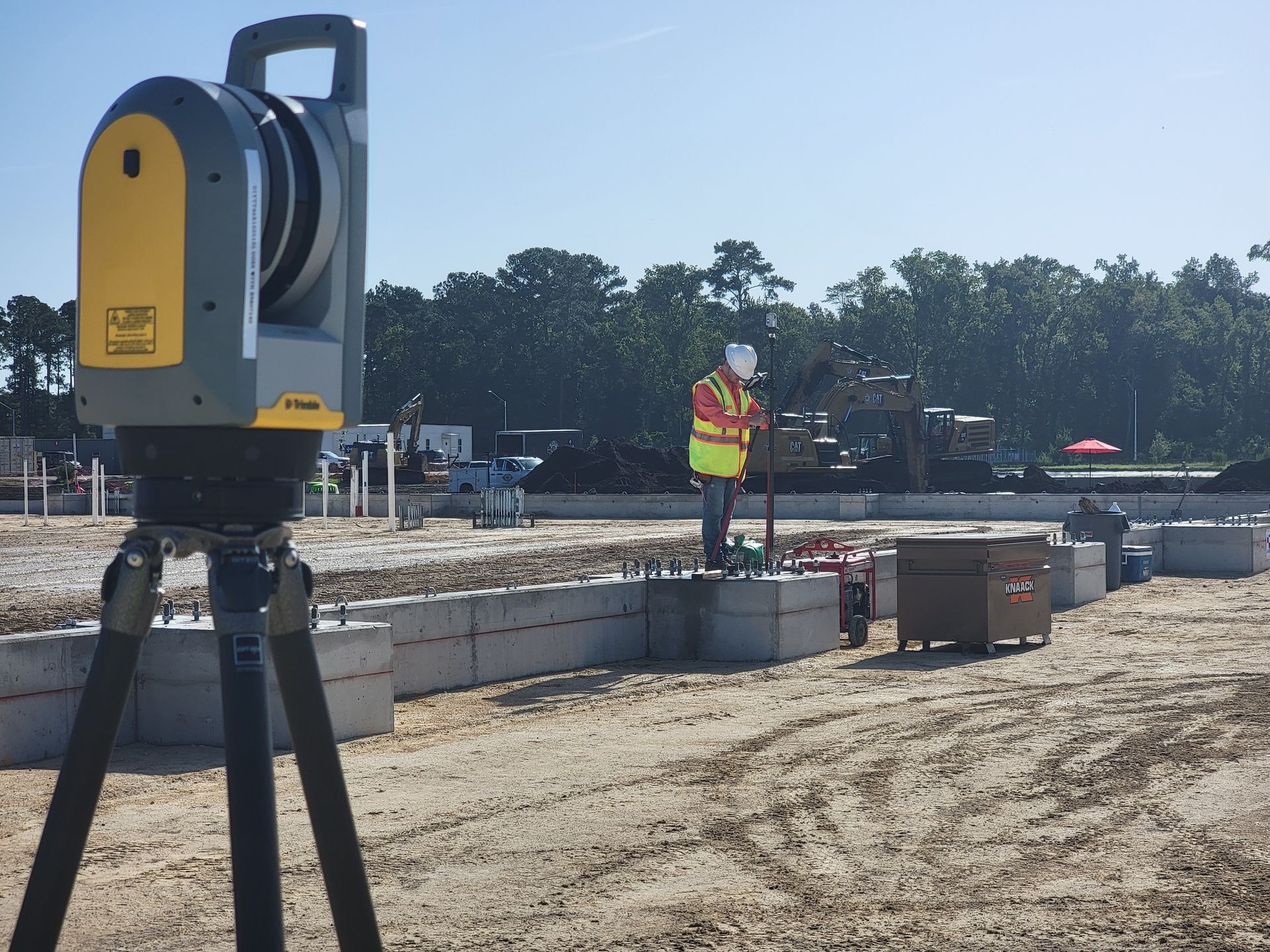 Surveyors on a construction project using terrestrial LiDAR and a robotic total station to measure as-built anchor bolts on an aircraft hanger.